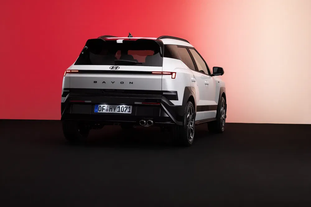 SUV Hyundai Bayon blanc sur fond dégradé rouge et rose, vue arrière élégante.