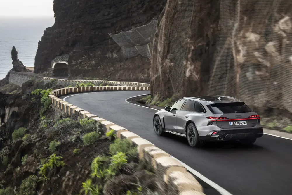 Audi op een kronkelende kustweg omringd door steile kliffen en weelderige begroeiing.