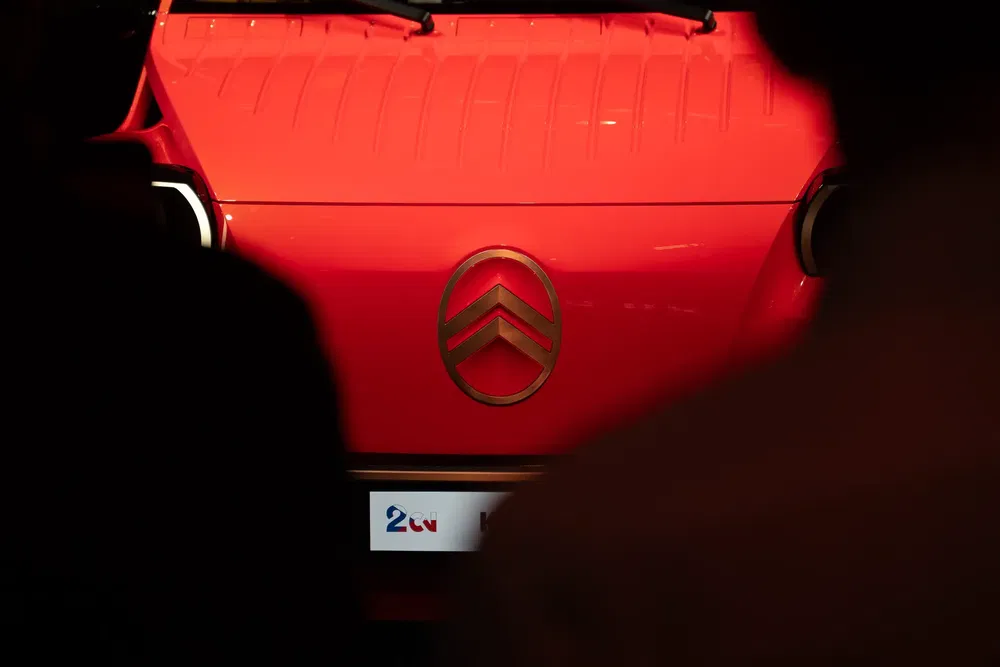 {"fr":"Vue avant d'une Citroën 2CV rouge avec logo distinctif en exposition.","nl":"Vooraanzicht van een rode Citroën 2CV met opvallend logo tentoongesteld."}
