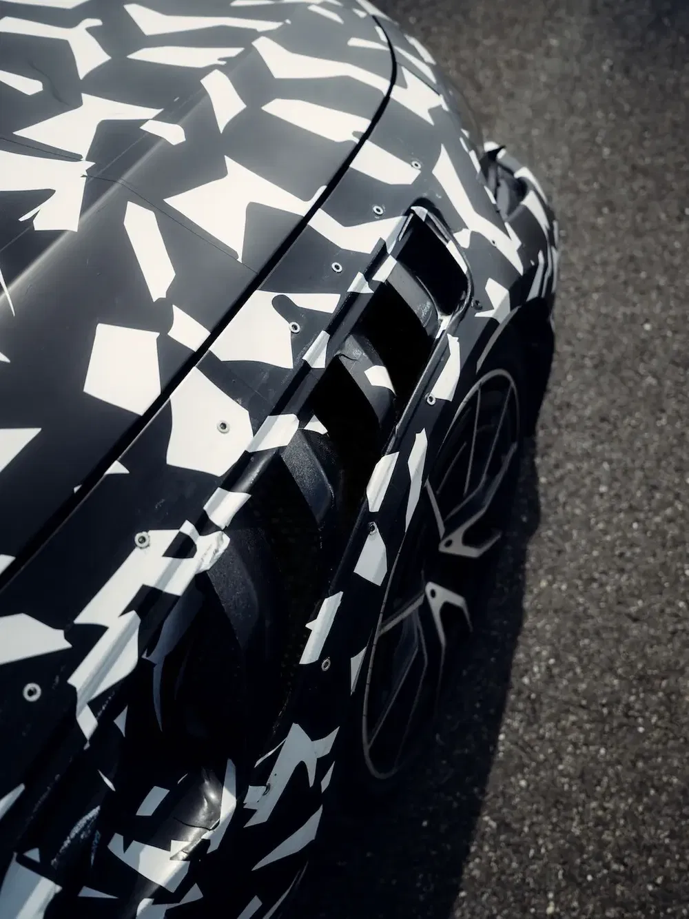 Auto met zwart-wit geometrisch camouflagepatroon, benadrukt sportieve aerodynamische lijnen.