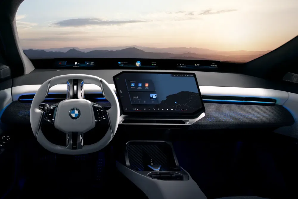Moderne BMW-interieur met panoramisch touchscreen en futuristisch stuur bij zonsopgang.