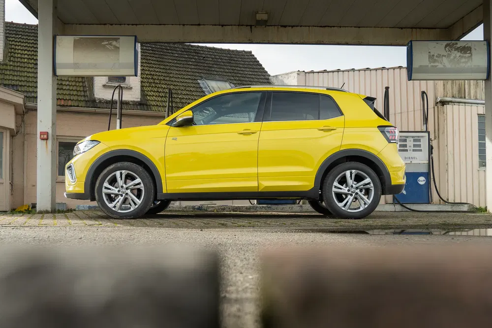 Gele Volkswagen T-Cross bij een verlaten tankstation.