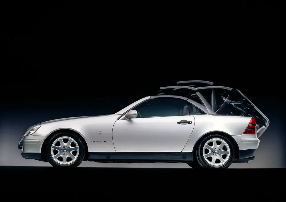 Mercedes-Benz SLK argent avec toit rétractable en mouvement, design élégant et sportif.