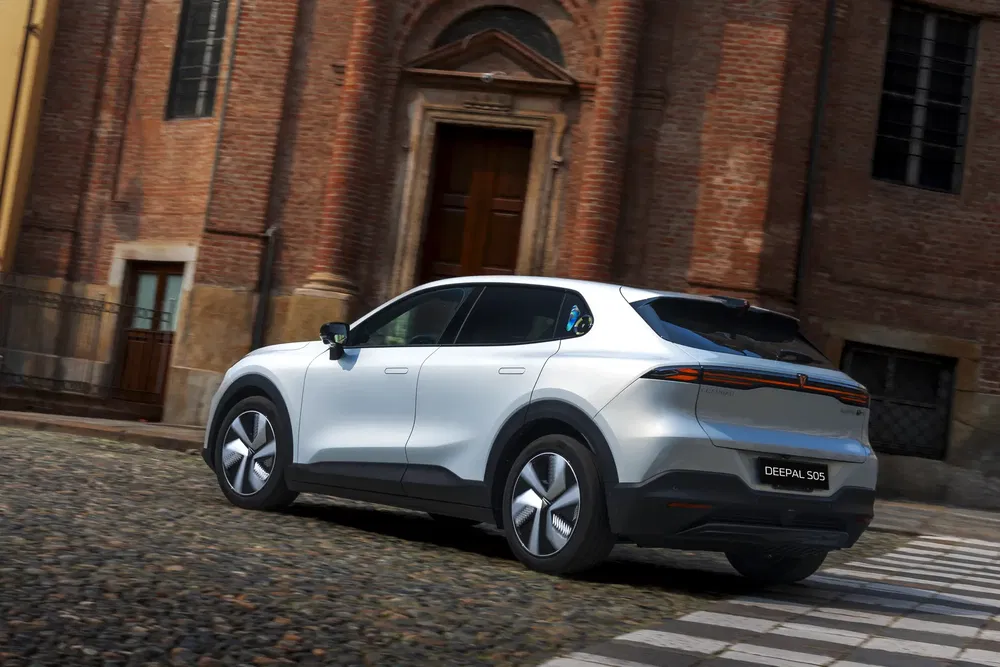 SUV électrique Deepal S05 blanc garé devant un bâtiment historique en briques.