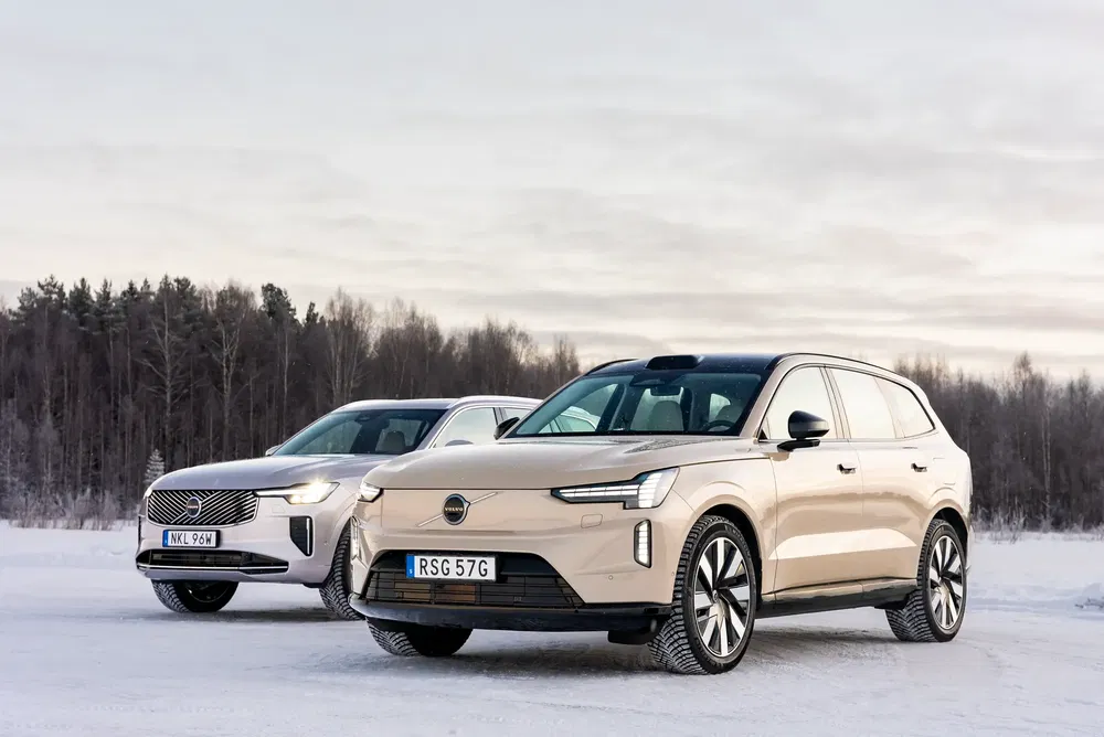 Deux SUV Volvo électriques sur neige, paysage forestier en arrière-plan.