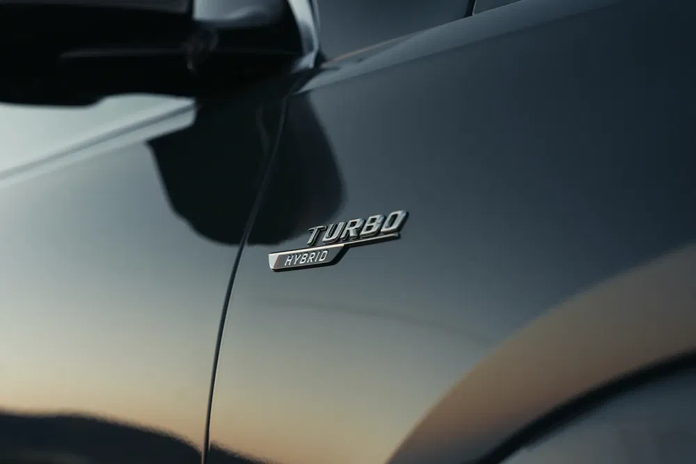 Turbo Hybrid-embleem op een donkere carrosserie bij zonsondergang.