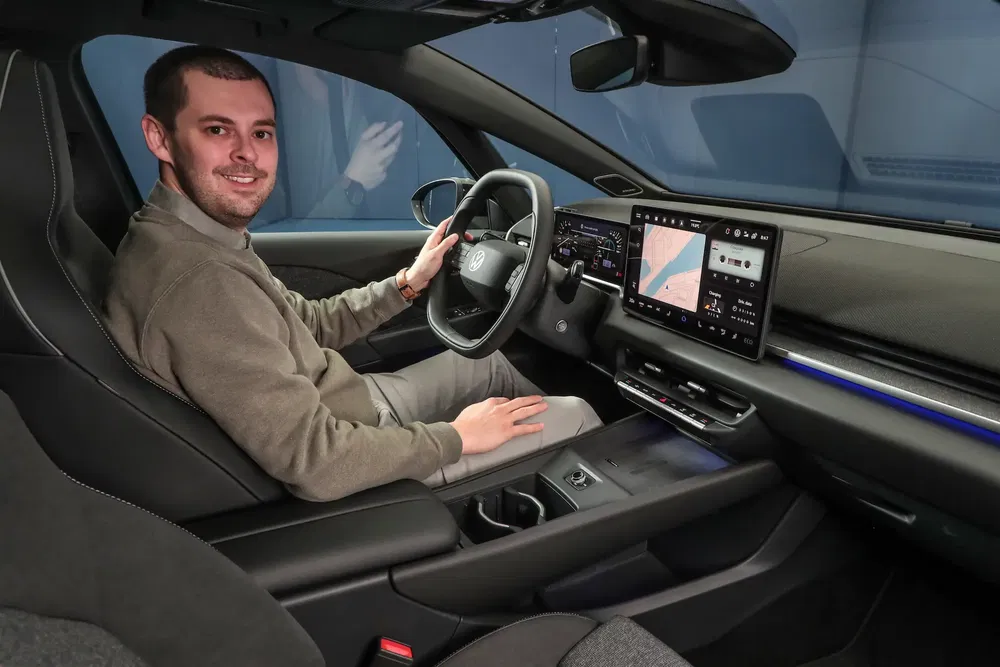 Intérieur d'une Volkswagen avec un tableau de bord numérique moderne et un homme au volant.
