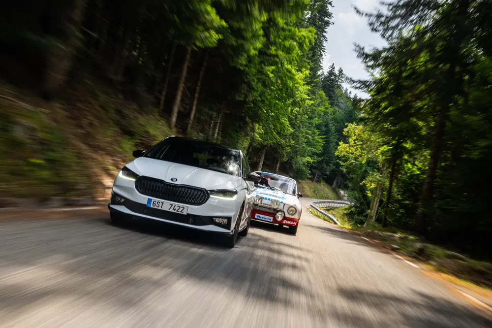 {"fr":"Deux voitures Skoda, une moderne et une classique, roulent sur une route de montagne boisée.","nl":"Twee Skoda-auto's, een moderne en een klassieke, rijden op een beboste bergweg."}