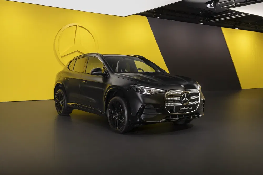 Mercedes-Benz GLA noir mat exposé sur fond jaune avec logo de l'étoile.