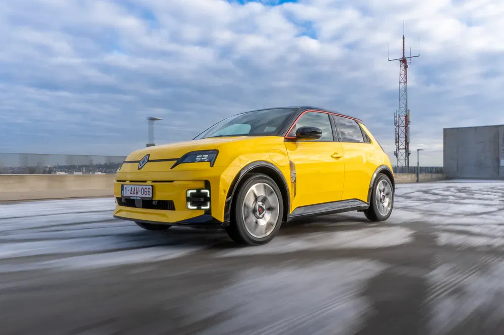 Voiture Renault jaune vif sur route glacée avec ciel nuageux en arrière-plan.
