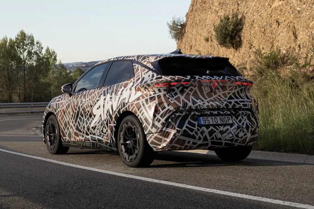 Elektrische SUV-prototype gecamoufleerd op een bochtige bergweg.