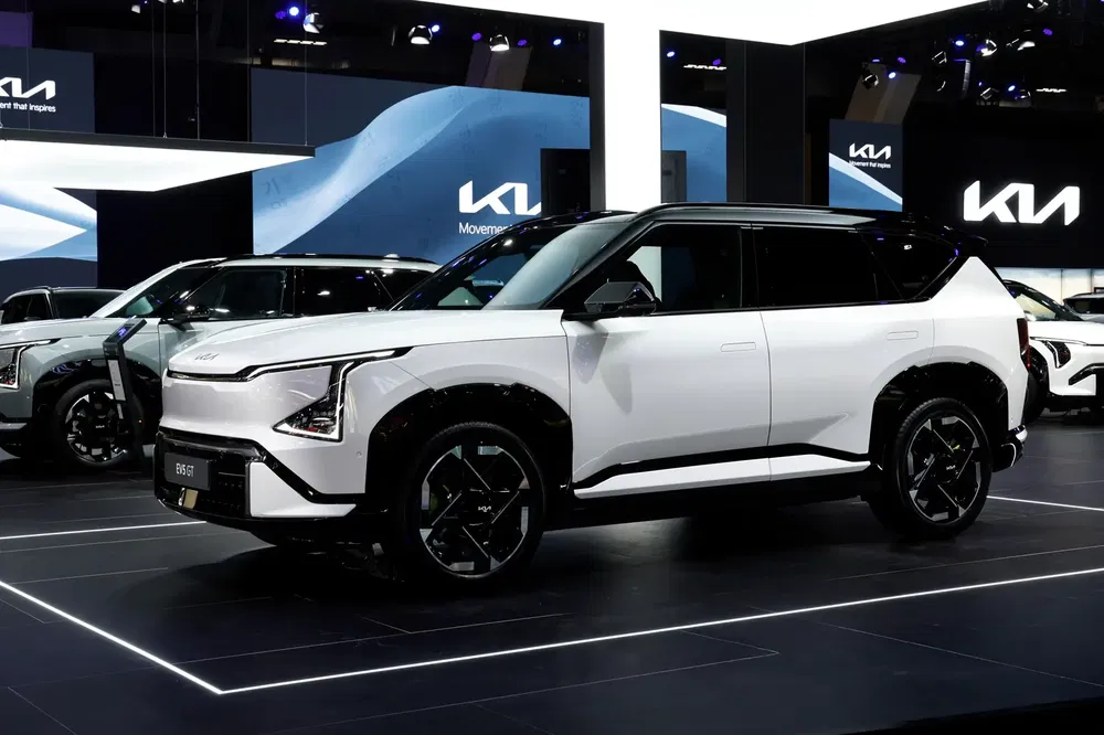 Nouveau SUV Kia blanc exposé lors d'un salon automobile, design moderne et élégant.