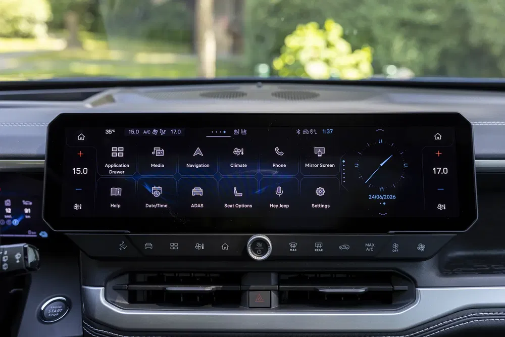 Intérieur Jeep avec écran tactile 15 pouces affichant navigation et commandes climatisation.