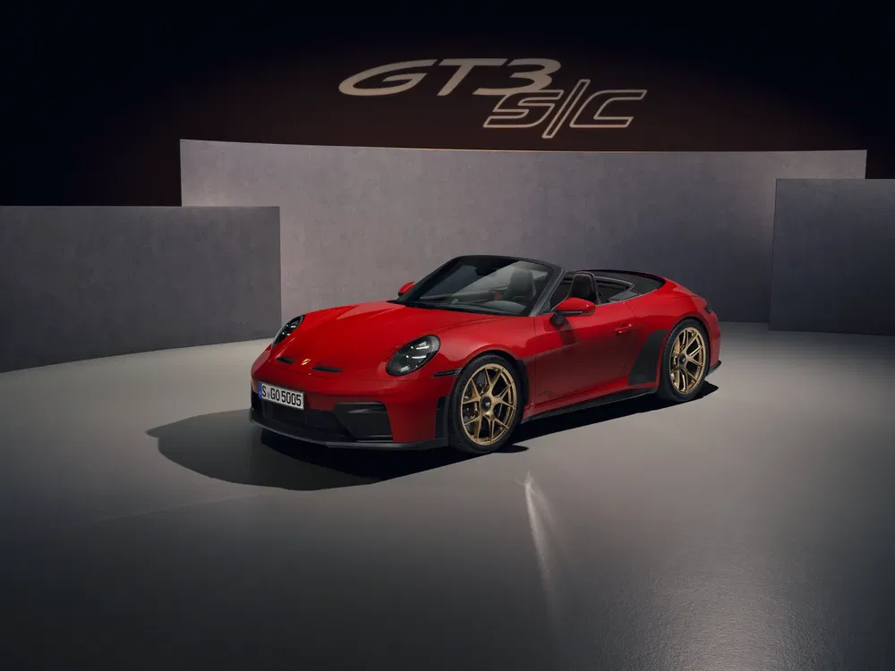 Porsche 911 GT3 rouge en exposition avec design moderne et jantes dorées.