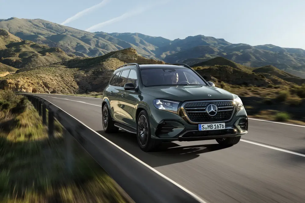 Mercedes-Benz SUV roulant sur une route de montagne pittoresque sous un ciel dégagé.