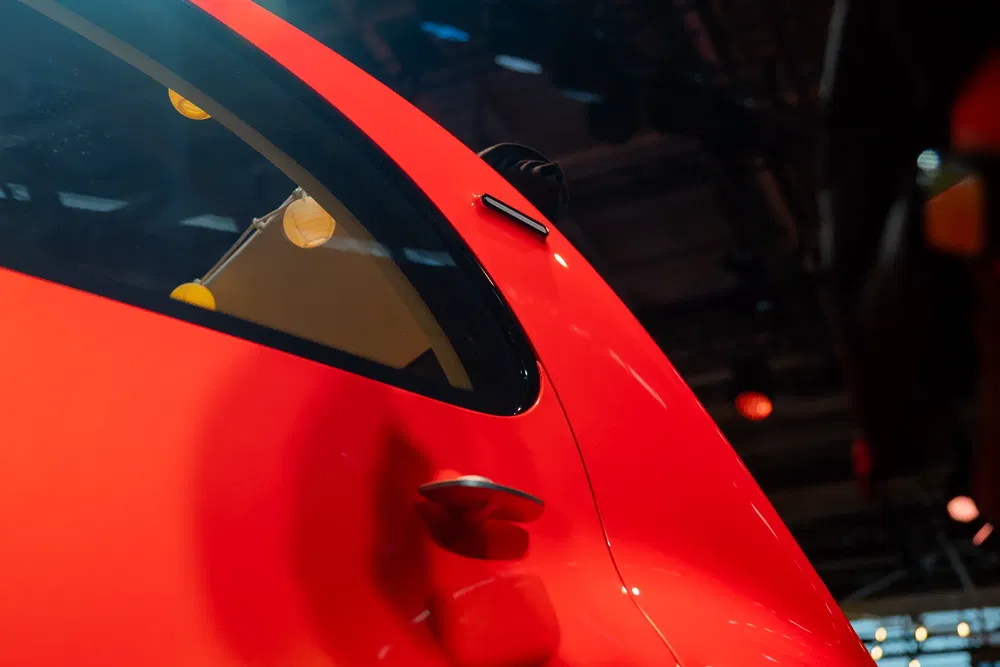 Nabij beeld van een glanzende rode auto met chromen handvat, verlichting autoshow.
