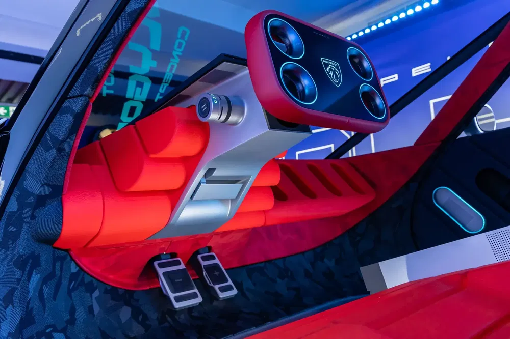 Intérieur futuriste de voiture concept Peugeot avec volant carré et sièges rouges innovants.