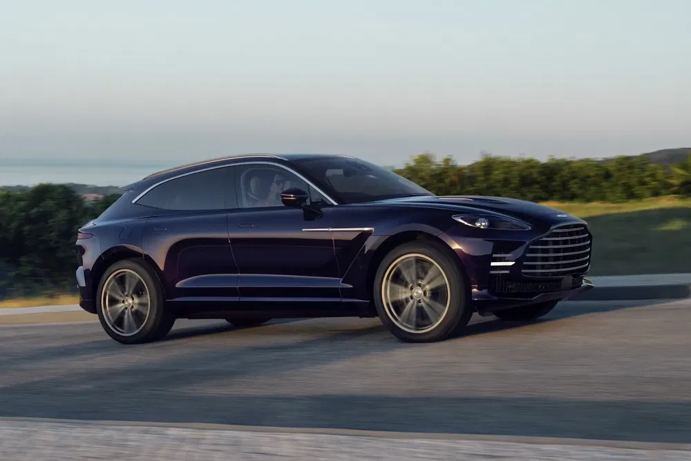 {"fr":"SUV Aston Martin DBX noir sur route, design élégant au coucher de soleil.","nl":"Zwarte Aston Martin DBX SUV op de weg, elegante stijl bij zonsondergang."}