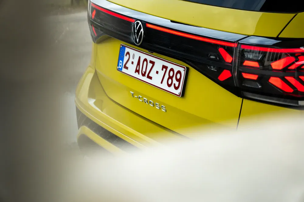 Gele Volkswagen T-Cross met Belgische kentekenplaat, stijlvolle moderne achterzijde.