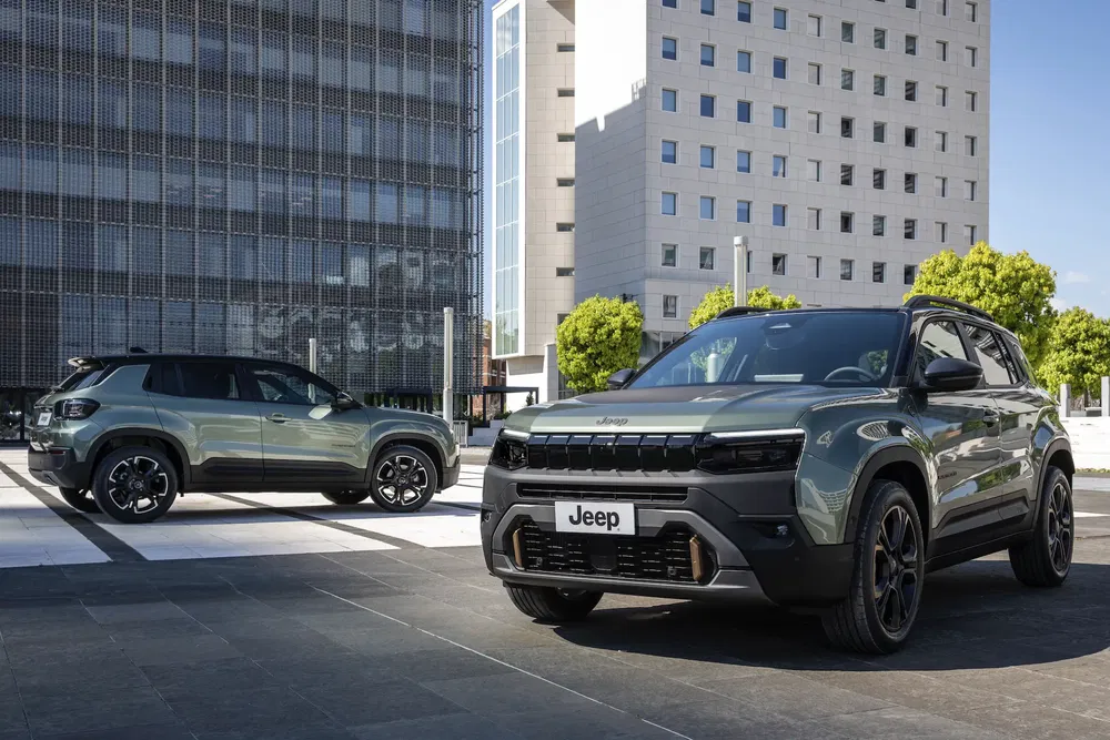 Deux Jeep Avenger modernes garées devant des immeubles de bureaux élégants en pleine ville.