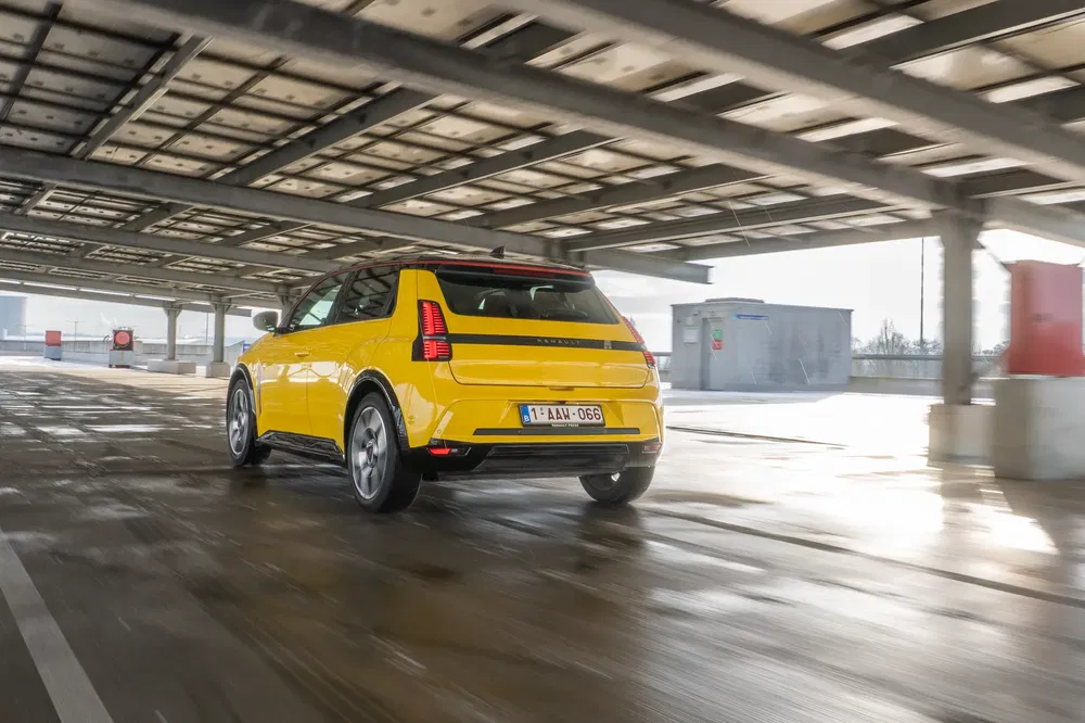 Voiture électrique jaune Renault sous abri, arrière profil, jour pluvieux.