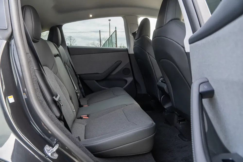 Ruime en moderne achterbank van een Tesla Model Y, grijze stoffering.