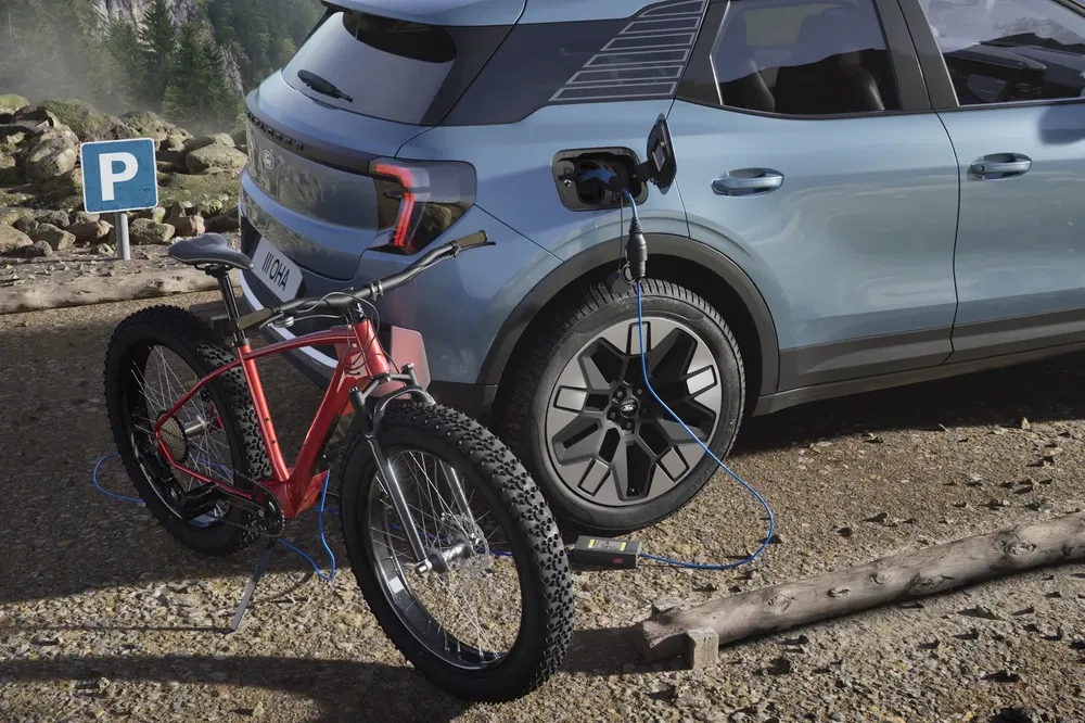 Ford Explorer électrique chargeant un vélo dans un parking en pleine nature.