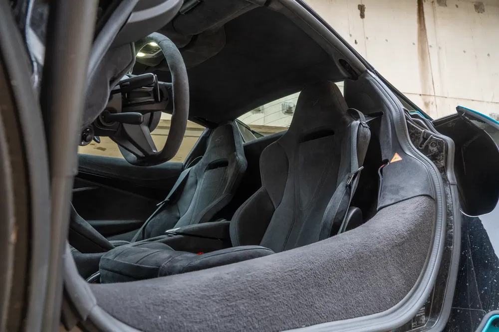 Intérieur de voiture de sport avec sièges baquets en alcantara, volant sportif exposé.