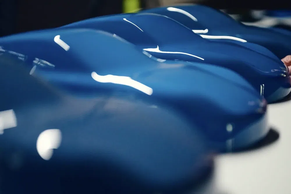 Gamme de modèles de voitures miniatures bleues alignées, montrant le design aérodynamique lisse.