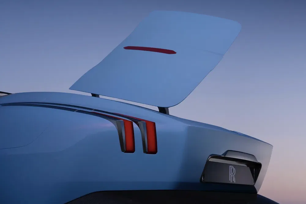 Open achterklep van een Rolls-Royce, kenmerkende achterlichten onder een heldere hemel.