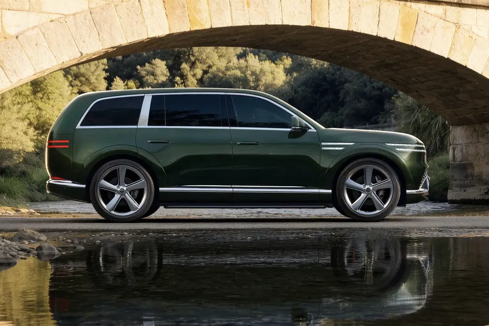 SUV électrique couleur vert émeraude sous un pont en pierre, reflet dans l'eau.