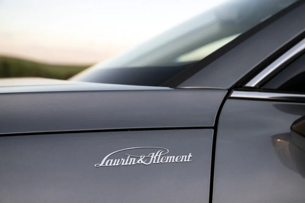 Gros plan sur le badge Laurin & Klement d'une voiture Škoda grise élégante.