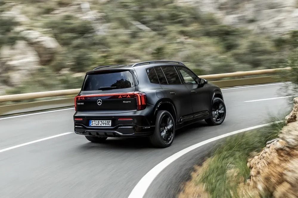 Mercedes EQB noir sur route sinueuse en montagne, arrière vue dynamique SUV électrique.