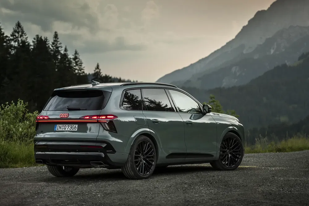 SUV Audi Q9 gris sur fond de montagne pittoresque au crépuscule.