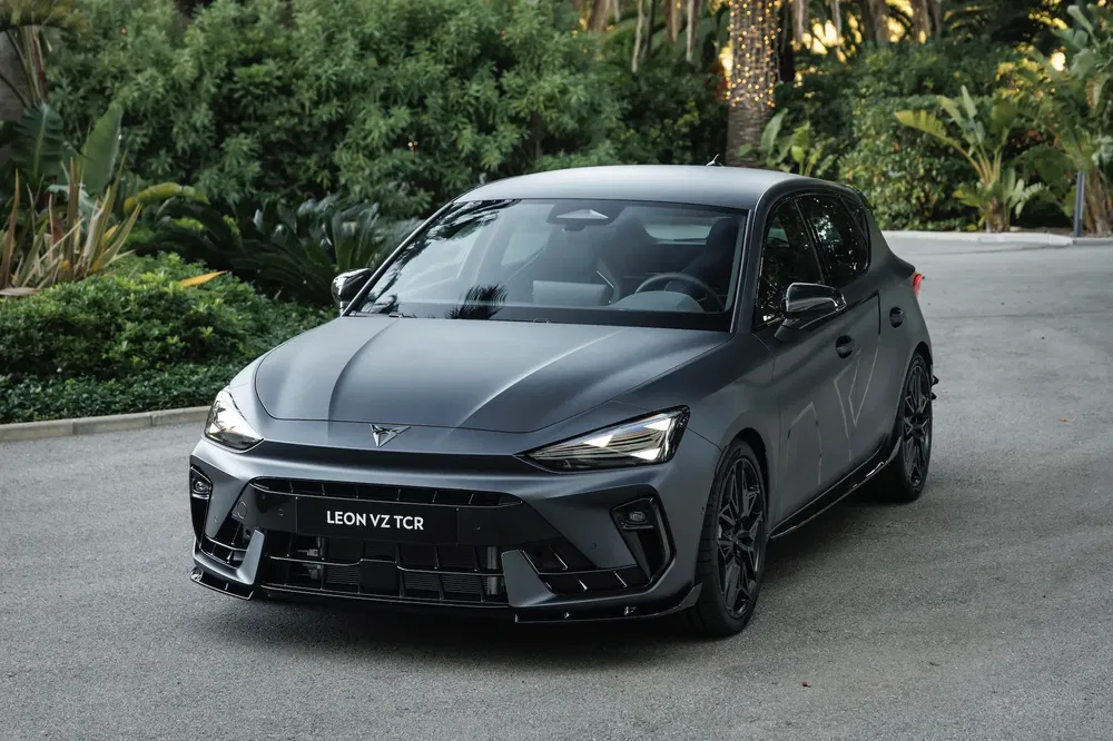 Matgrijze Cupra Leon VZ TCR voor weelderige groene achtergrond op geplaveide weg.