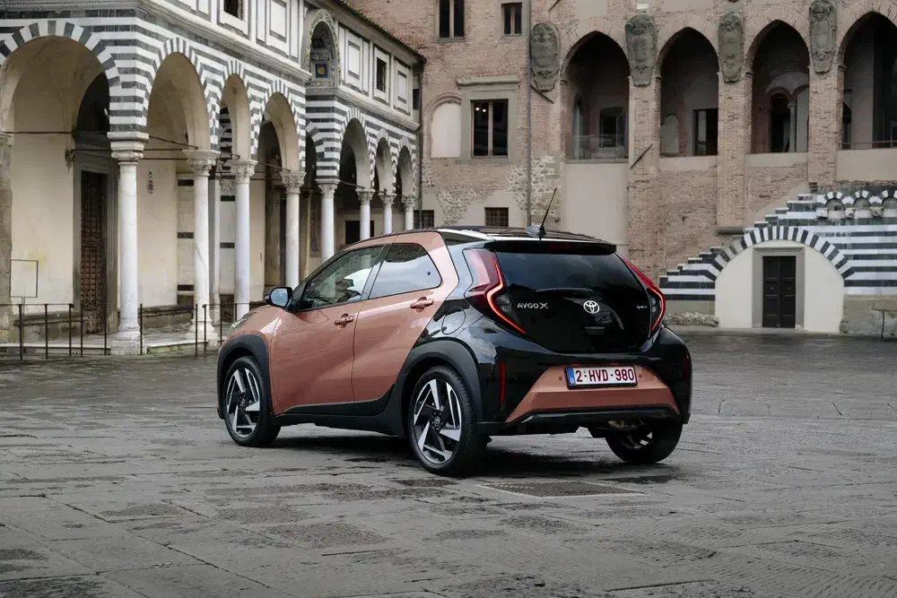 Toyota Aygo X geparkeerd in historische binnenplaats, compact en modern stadsontwerp.