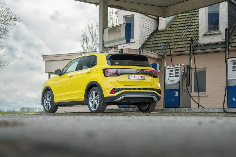 Gele Volkswagen Taigo bij een ouderwets tankstation op het platteland.