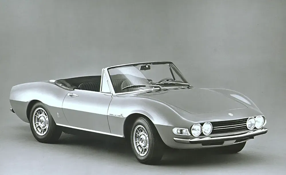Voiture classique cabriolet Fiat avec carrosserie élégante et quatre phares ronds distinctifs.