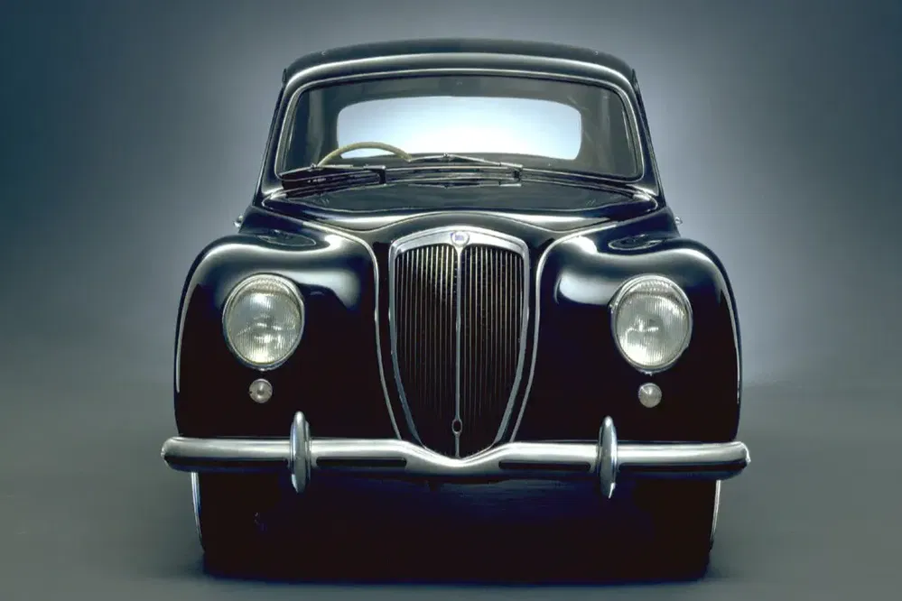 Voiture classique noire de face avec calandre emblématique, phares ronds, et pare-chocs chromé.