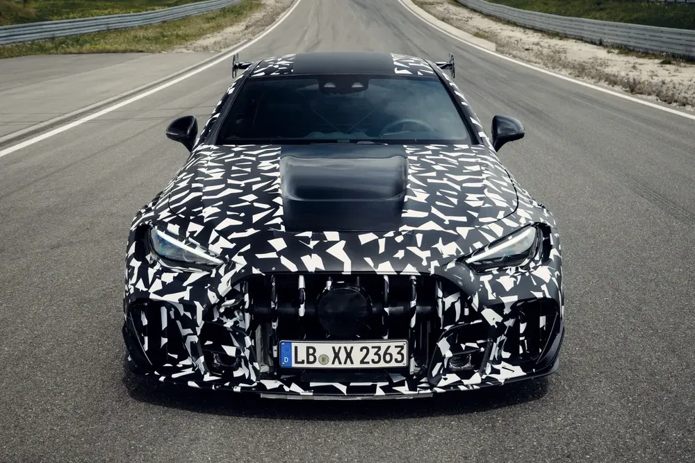 Voorkant camouflaged sportwagen op testbaan met Duitse nummerplaat, agressief ontwerp.