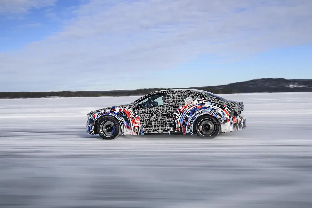 Gecamoufleerde auto testend op ijsweg onder deels bewolkte hemel, besneeuwd landschap.