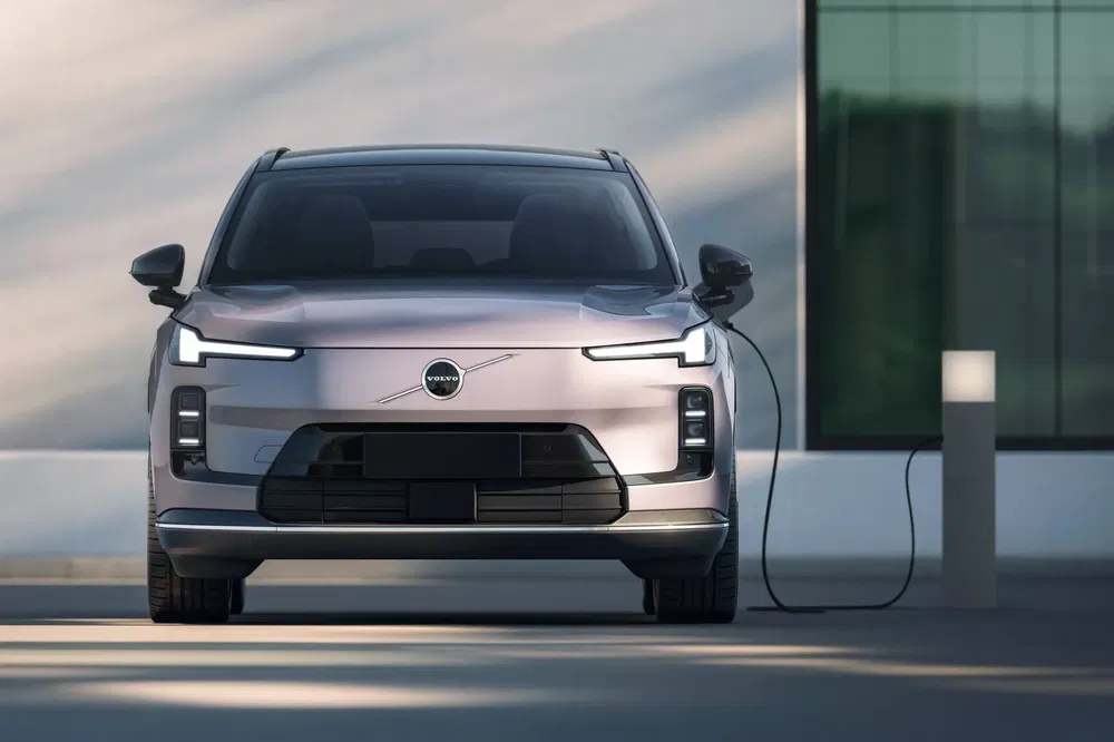 Voiture électrique Volvo en charge, design avant moderne et épuré, murs vitrés en fond.