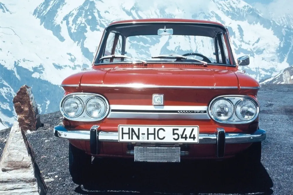 Rode klassieke NSU-auto voor besneeuwde berglandschap.