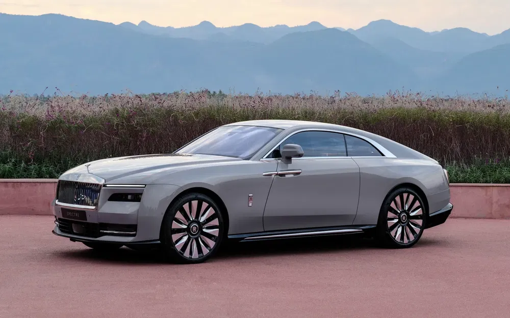 Rolls-Royce Spectre élégante, grise, devant un paysage de montagnes lointaines.
