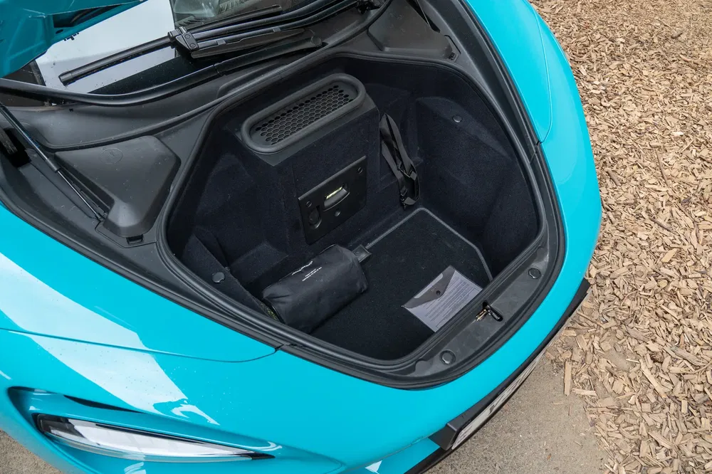 Coffre avant d'une voiture de sport bleu vif, avec rangement compact et accessoire noir.
