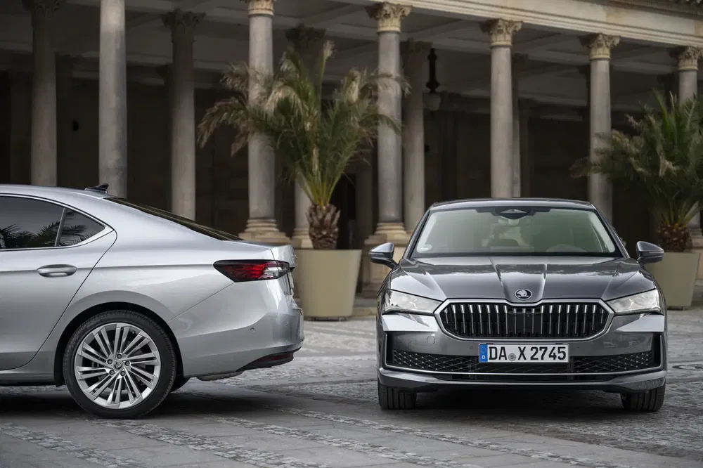 Deux berlines Skoda garées devant une colonnade avec des palmiers.