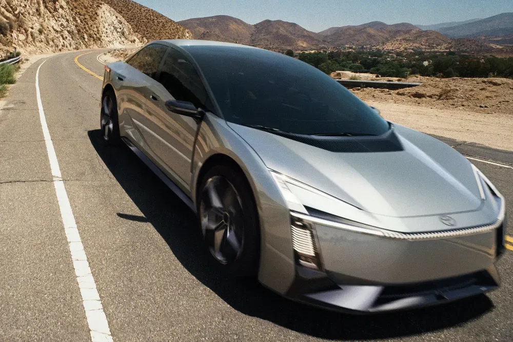 Voiture électrique futuriste argentée sur route de montagne sinueuse.