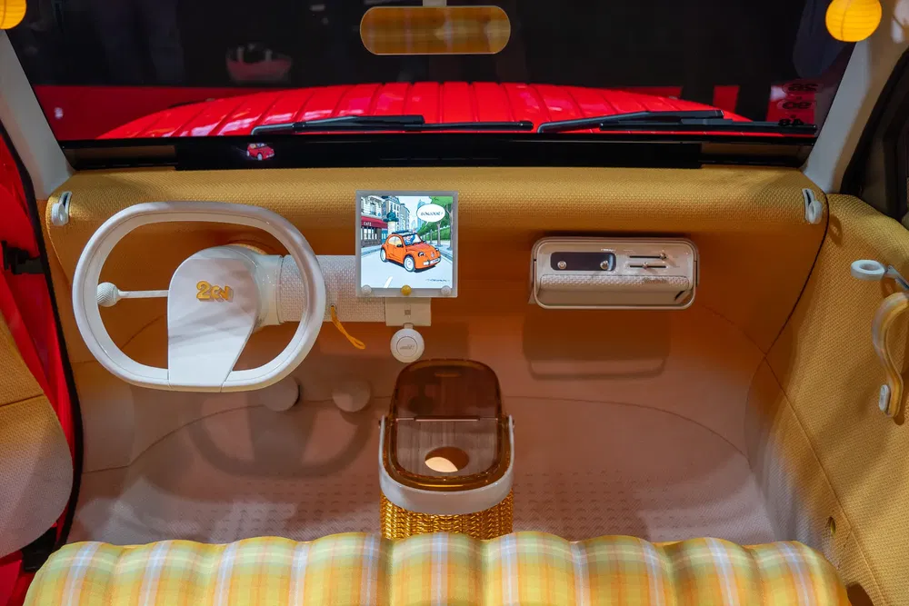 Retro interieur van een Citroën 2CV met uniek stuur en opvallend centraal scherm.