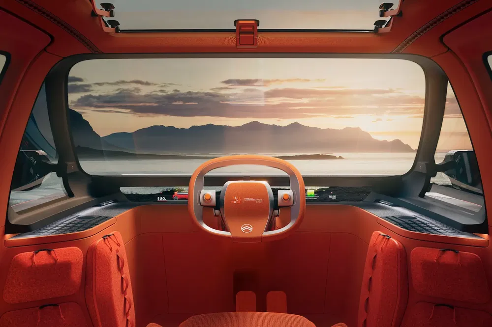 Intérieur spacieux du concept car Citroën, volant futuriste avec vue panoramique sur coucher de soleil.