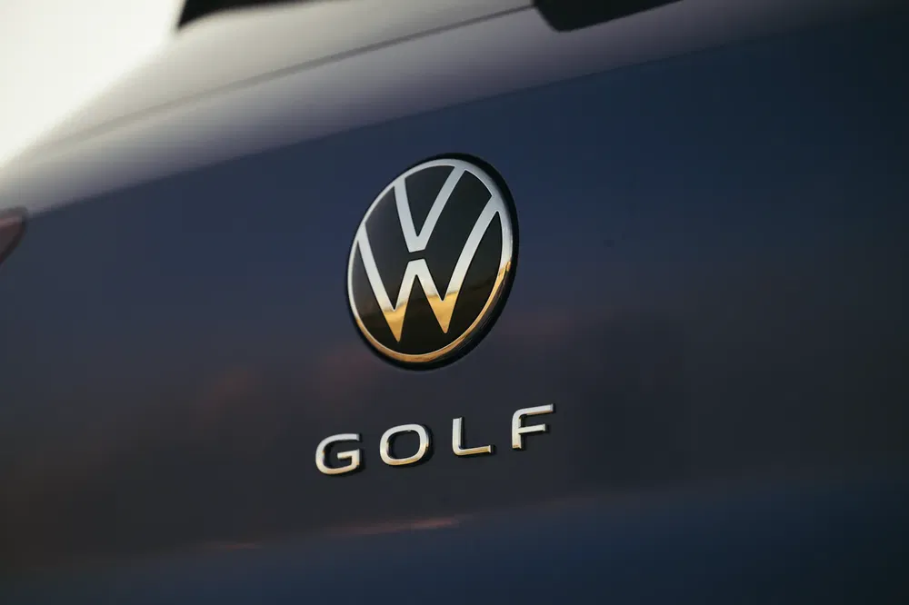 {"fr":"Logo Volkswagen sur hayon d'une Golf, reflet du coucher de soleil sur le métal bleu.","nl":"Volkswagen-logo op achterklep van Golf, zonsondergang reflectie op blauwe metaalkleur."}